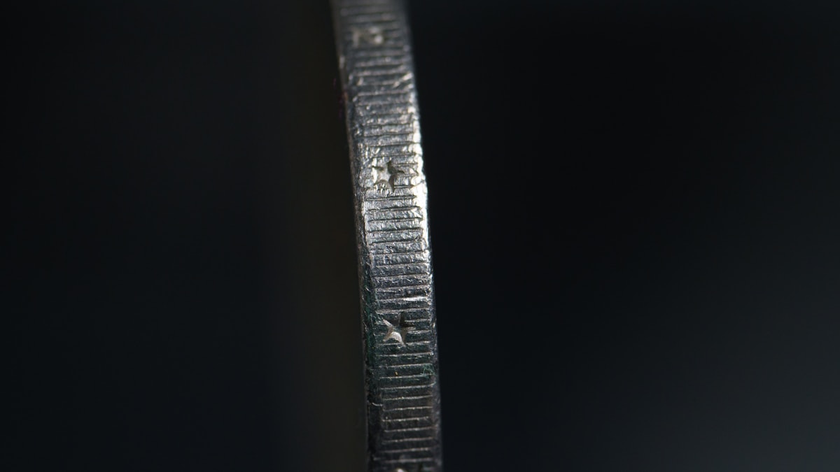 Macro detail focusing on worn calipers, steel rulers, and brushed steel offcuts on a shop floor.